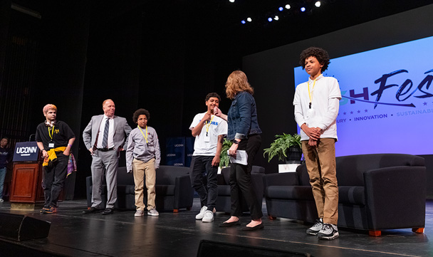 Sandra Chafouleas gives a student a fist bump while others look on from the stage