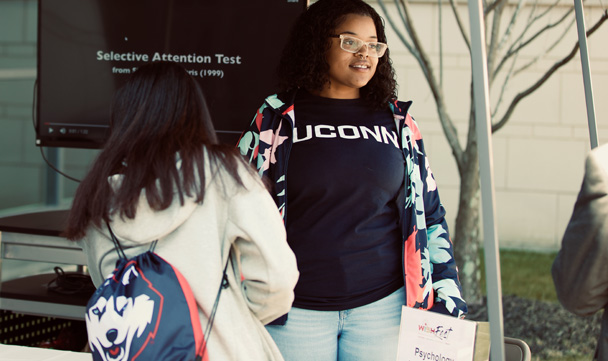 Two attendees stand outside, one with a UConn t-shirt and the other with a Huskies backpack.