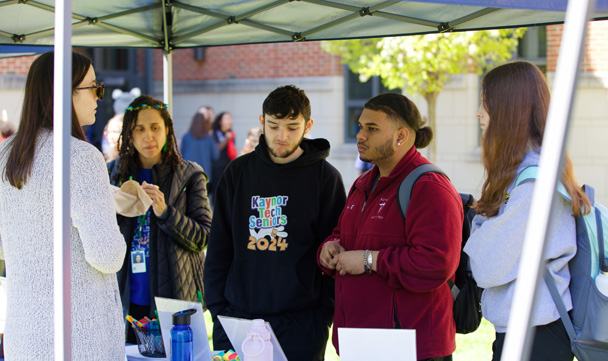 Students engage with an exhibit under a tent.